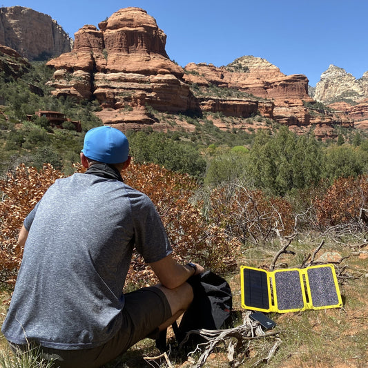 Backpacker charging a phone with a SunJack solar panel